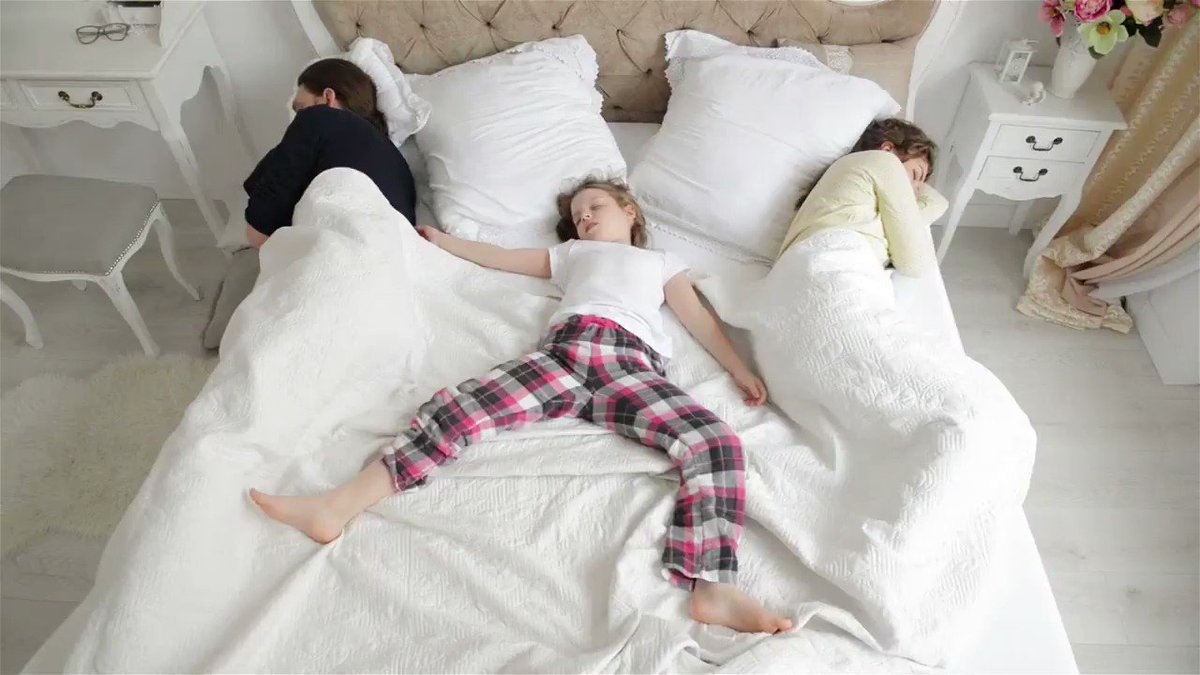 Ребенок на кровати посередине между стесненными им родителями